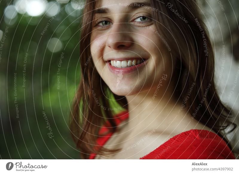 Junge Frau mit Grübchen lächelt und schaut in die Kamera, während sie in der Natur steht brünett sportlich 18-30 Jahre Erwachsene langhaarig ästhetisch