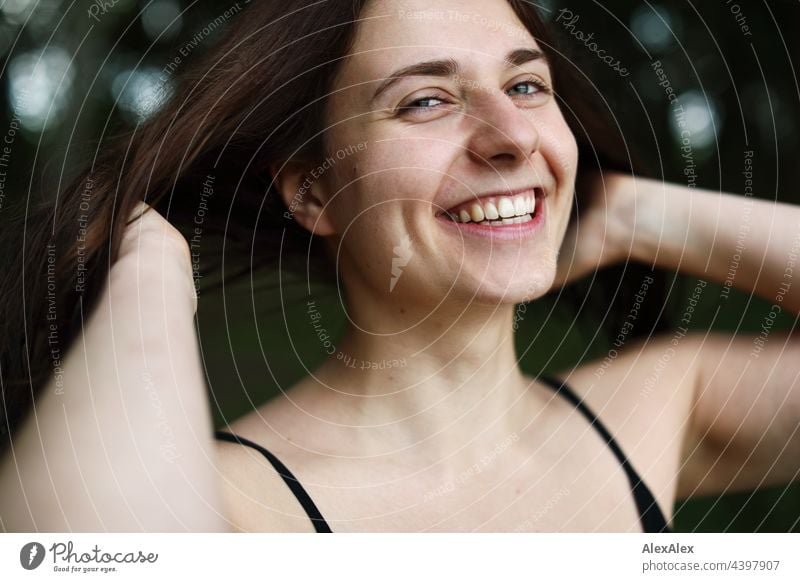 Junge Frau mit Grübchen hält die Hände zur Seite und lächelt Natur brünett sportlich 18-30 Jahre Erwachsene langhaarig ästhetisch Jugendliche Identität