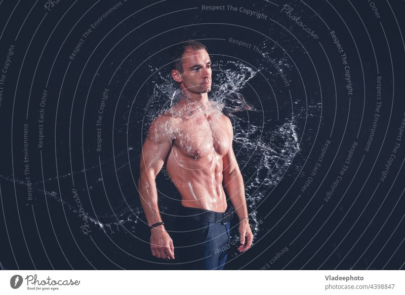 Muskulöser Fitness-Mann in nasser Kleidung unter Regen mit Wasserspritzern auf dunklem Hintergrund. aqua Porträt Bauchmuskeln platschen frisch Gesundheit