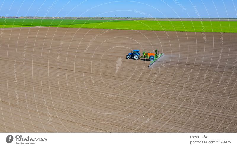 Luftaufnahme eines Traktors beim Besprühen eines Feldes mit Sprühgerät, Herbizid und Pestizid oben Antenne Aerosol landwirtschaftlich Ackerbau anbaufähig