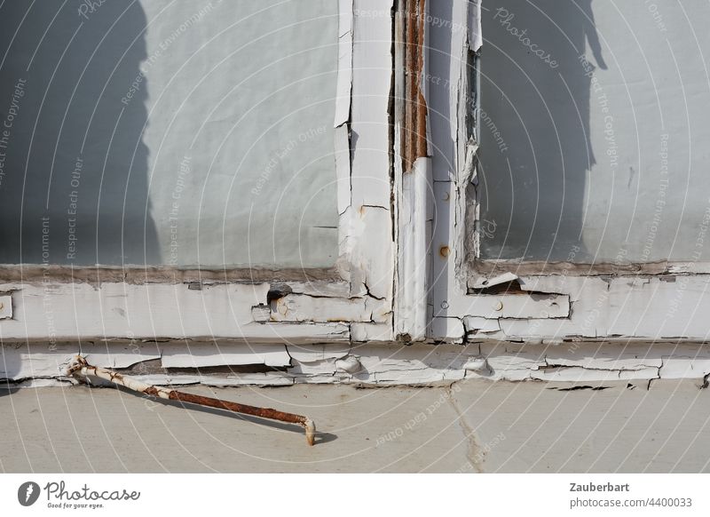 Alter Fensterrahmen mit abblätternder weißer Farbe und einem abgelegten Haken an einem leerstehenden  Haus ablegen alt verfallen Holz Vergänglichkeit Lack