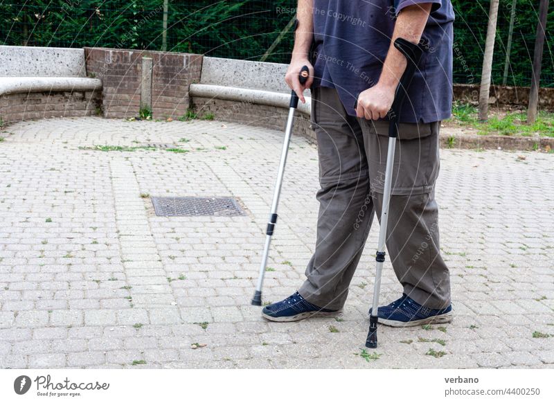 Mann, der mit Hilfe von zwei Greifzangen geht Schmerz Senior Gesundheit älter Textfreiraum Lifestyle laufen Spaziergang Menschen im Freien Porträt Sommer