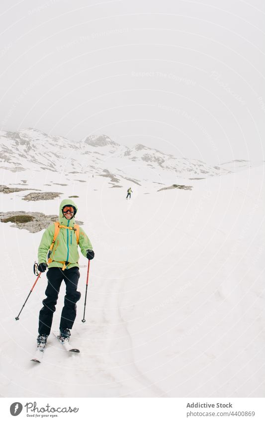 Lächelnder Skifahrer mit Skibrille auf einem verschneiten Bergrücken im Winter Skifahren Sport Schnee Berge u. Gebirge Natur Hochland Mann Sportler Freund