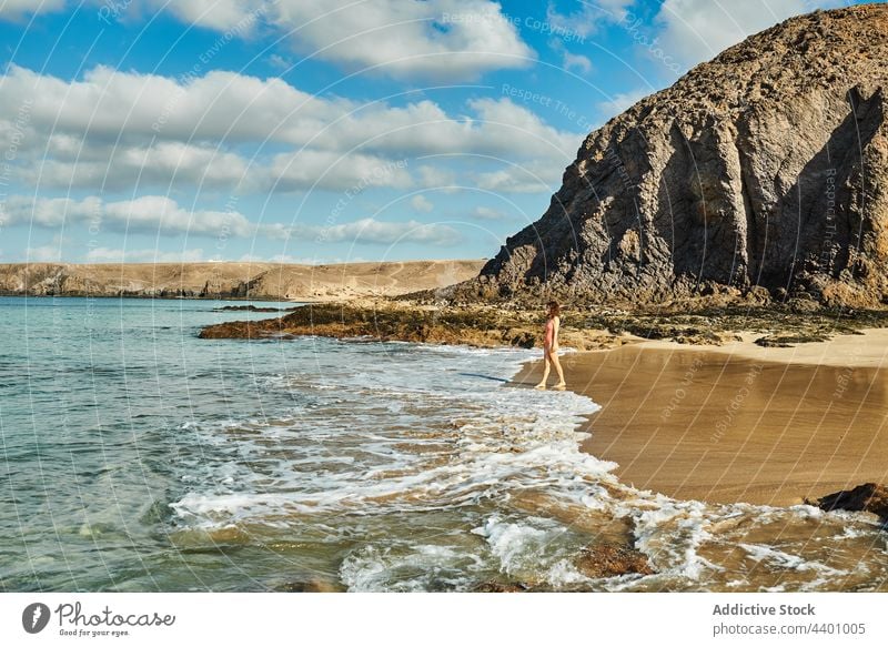Frau steht in der Nähe des wogenden Meeres am Strand MEER winken Tourist Sommer Urlaub Klippe Blauer Himmel wolkig Fuerteventura Spanien Kanarische Inseln Küste