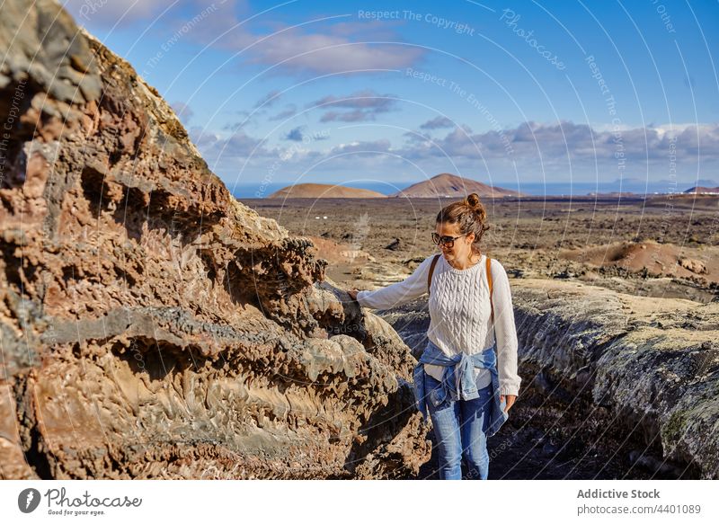 Weiblicher Reisender berührt felsige Oberfläche Frau Spaziergang Hochland berühren Felsen Formation erkunden Ausflug Sommer Wochenende Fuerteventura Spanien