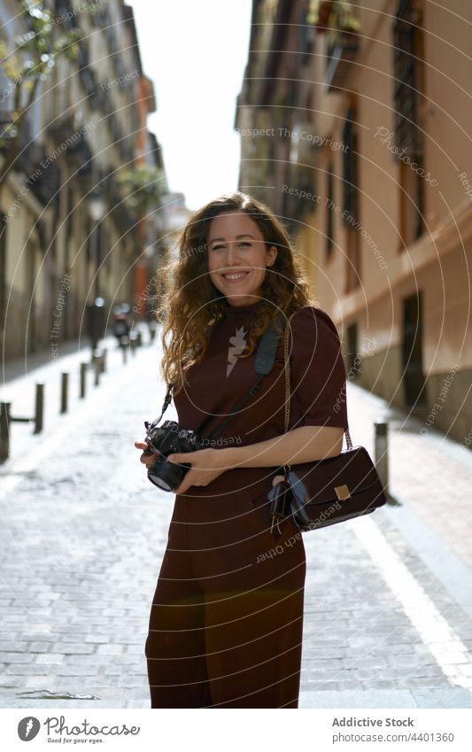 Fröhlicher Fotograf mit digitaler Fotokamera auf städtischem Bürgersteig Fotoapparat heiter nachdenken herzlich freie Zeit Straße Großstadt Frau Inhalt charmant
