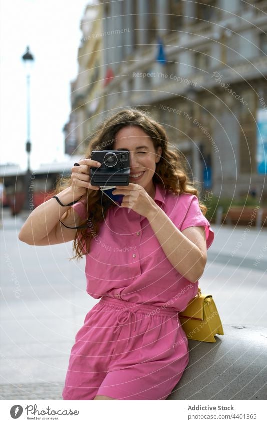 Lächelnde Frau beim Fotografieren mit einer Sofortbildkamera in der Stadt fotografieren Fotoapparat sofort Fokus Gedächtnis Moment heiter benutzend Gerät