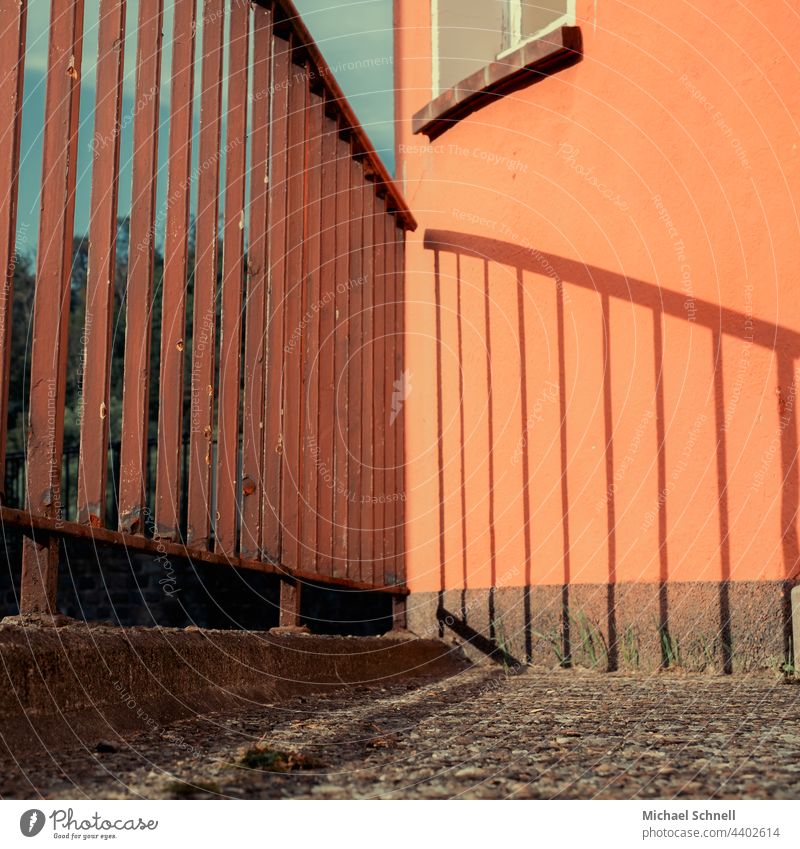 Schattenwurf eines Geländers Abgrenzung Schutz Metall Sicherheit Zaun Grenze Menschenleer orange Schattenspiel