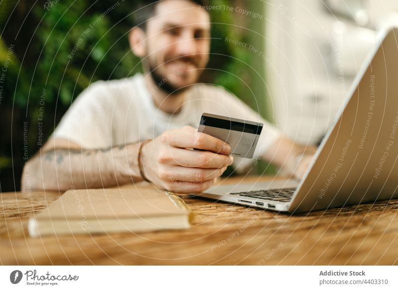 Mann beim Bezahlen mit Plastikkarte beim Online-Shopping Zahlung online Werkstatt Laptop Kauf bezahlen Orden Käufer e-Commerce Kunde verbrauchen Laden