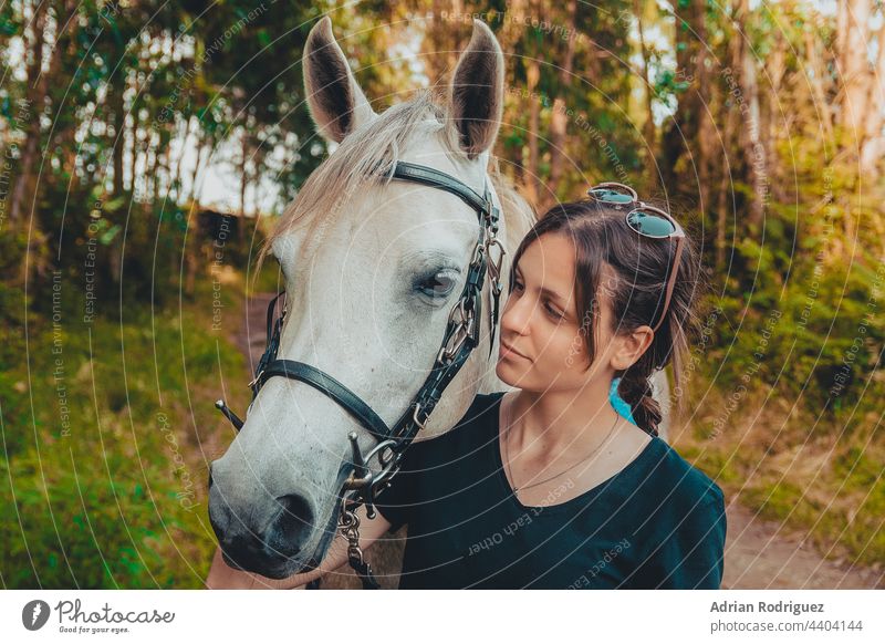 Junge Frau, die sich darauf vorbereitet, Reitlehrerin zu werden, kümmert sich um ein Pferd und spricht mit ihm an einem heißen Herbsttag Mädchen Tier Natur jung