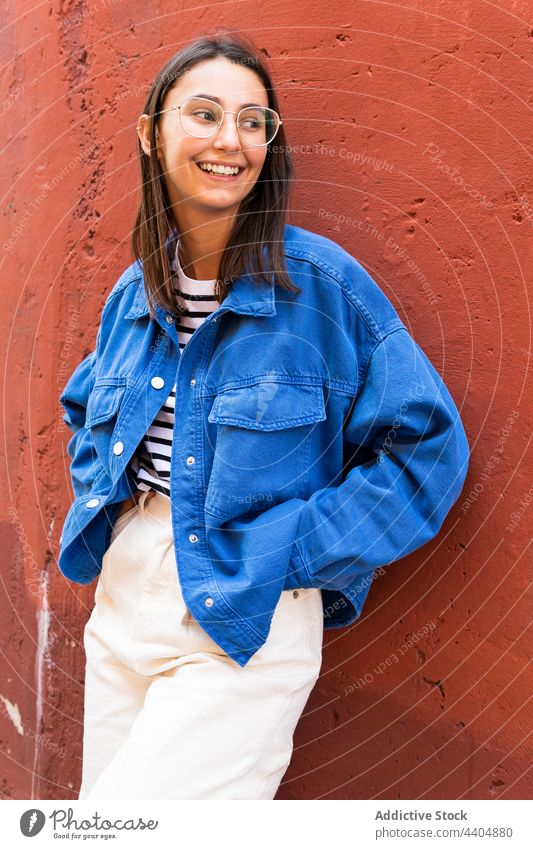 Glückliche Frau lächelt an einem sonnigen Tag in der Stadt heiter Freude Stil urban Straße Großstadt Gebäude Wand Lächeln trendy Outfit farbenfroh Lehnen