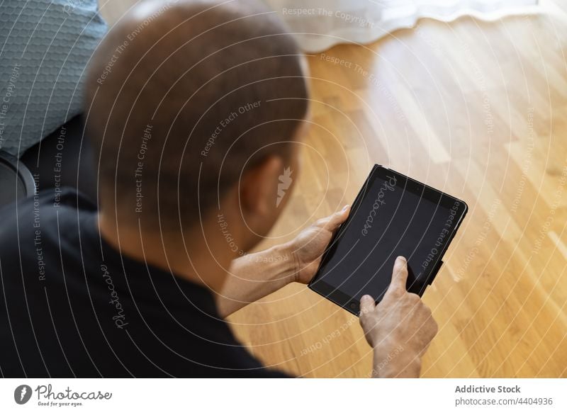 Anonymer ernster Mann, der morgens zu Hause auf seinem Tablet surft benutzend Tablette Browsen Morgen heimwärts Internet Surfen Fokus männlich Erwachsener
