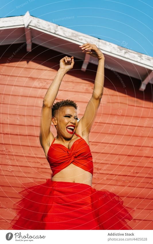 Aufgeregte schwarze Frau in rotem Kleid tanzend und schreiend Tanzen Arme hochgezogen Mode Stil Energie aufgeregt Spaß haben Make-up Individualität cool