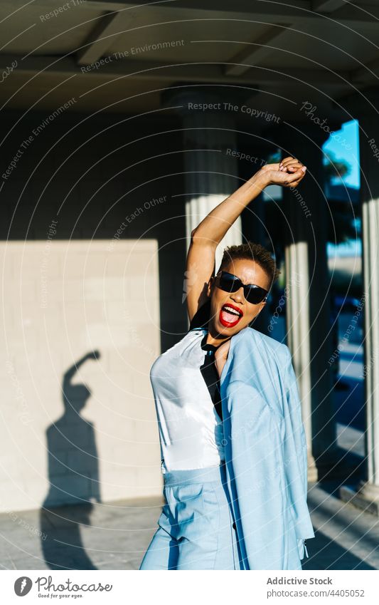 Glückliche schwarze Frau in trendiger Kleidung in der Stadt Mode Stil Spaß haben Individualität Sonnenbrille Energie stylisch stehen Mund geöffnet heiter