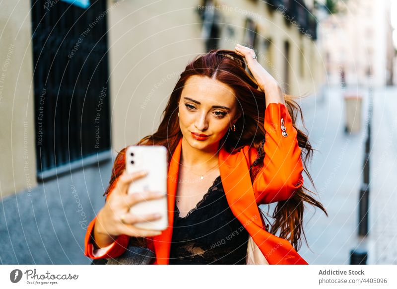 Trendy rothaarige Frau nimmt Selfie in der Stadt Smartphone Rotschopf Ingwer Großstadt Selbstportrait orange lebhaft Farbe Straße Stil urban Mode Gedächtnis
