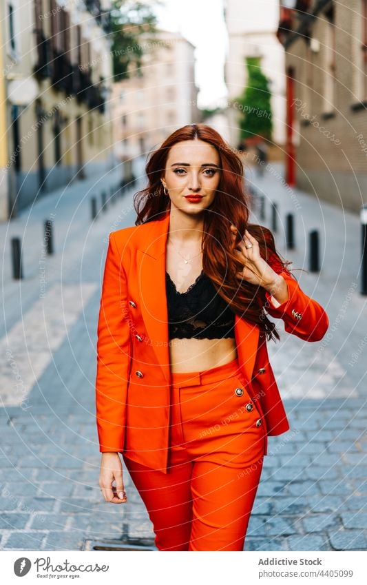 Rothaarige Frau in orangefarbenem Anzug in einer Straße in der Stadt Stil trendy hell Farbe Spaziergang Rotschopf Großstadt Outfit Mode selbstbewusst Vorschein
