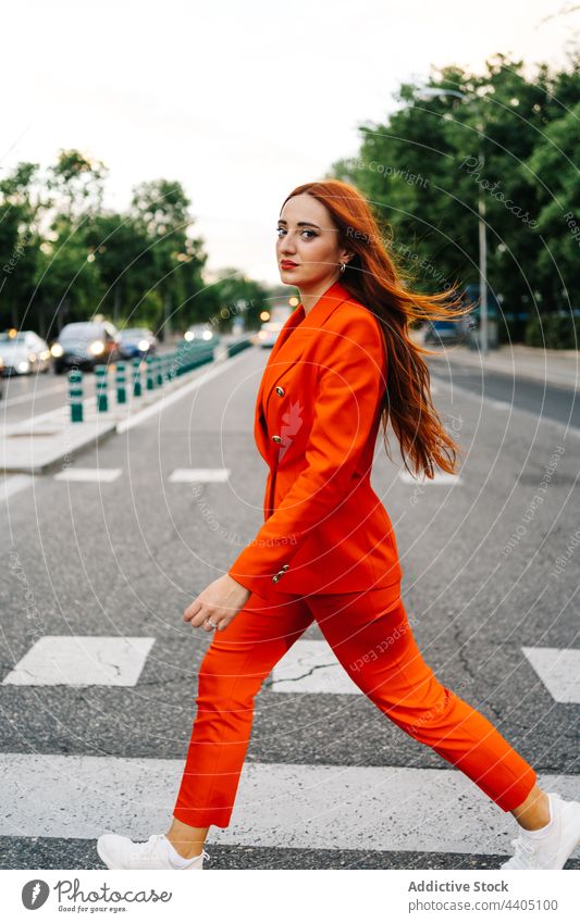 Trendige rothaarige Frau beim Überqueren der Straße in der Stadt durchkreuzen Zebrastreifen Anzug orange lebhaft Stil Rotschopf Ingwer Mode Großstadt