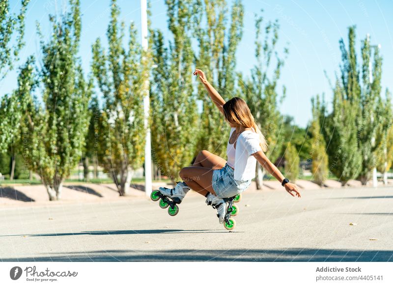 Frau balanciert auf einem Rad in Rollerblades und zeigt Stunt Gleichgewicht Trick Ausgeglichenheit Skater Sommer Straße Aktivität üben sonnig Sonnenlicht