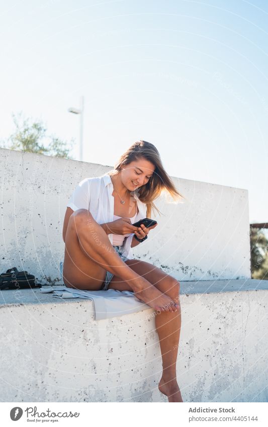 Lächelnde Frau, die auf der Straße auf ihrem Smartphone surft Großstadt Sommer Moment Glück heiter Text Nachricht Browsen Mobile Gerät Funktelefon benutzend