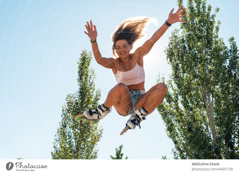 Energiegeladene Frau springt mit Rollschuhen im Park springen Rollerblade Trick Stunt aktiv Sommer Moment Aktivität Bewegung dynamisch Sonnenlicht Freiheit