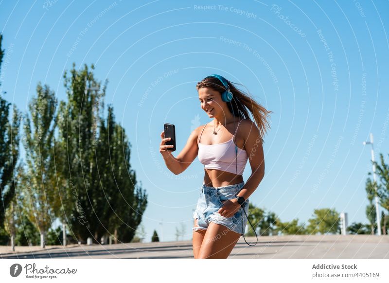 Lächelnde Frau in Rollschuhen macht Selfie auf der Straße Rollerblade Smartphone Großstadt Sommer Selbstportrait Moment Skater Glück heiter Musik Gedächtnis