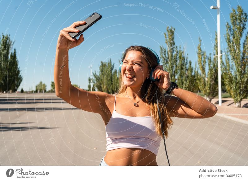 Lächelnde Frau in Rollschuhen macht Selfie auf der Straße Rollerblade Smartphone Großstadt Sommer Selbstportrait Moment Skater Glück heiter Musik Gedächtnis