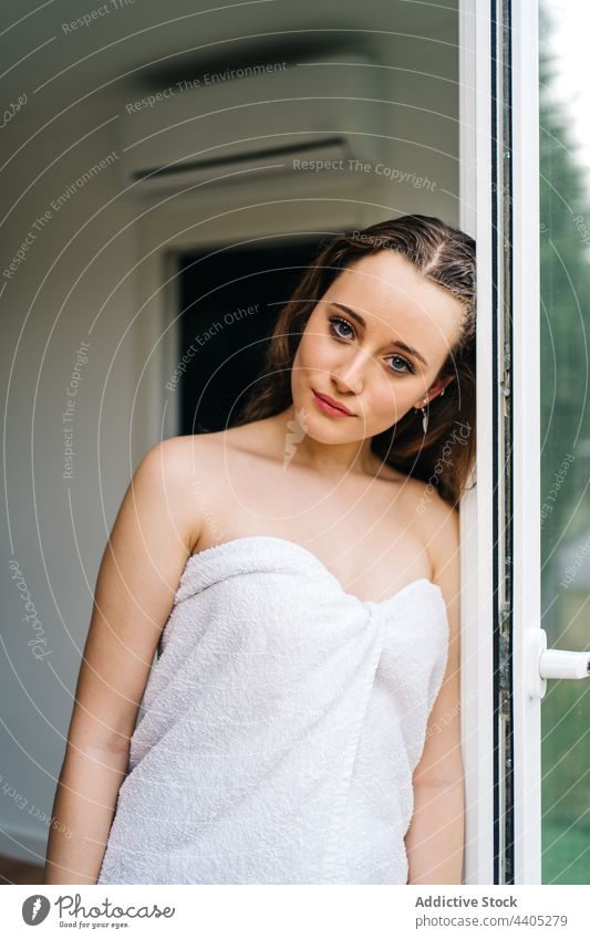 Zarte Frau im Handtuch steht in der Nähe der Tür auf dem Balkon nass frisch Sauberkeit nasses Haar Hygiene sanft filigran Angebot Pflege Körper natürlich
