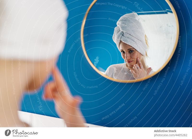 Charmante Frau cremt sich im Bad vor dem Spiegel ein bewerben Sahne Hautpflege Routine Morgen Schönheit Gesichtsbehandlung Leckerbissen täglich Handtuch Turban