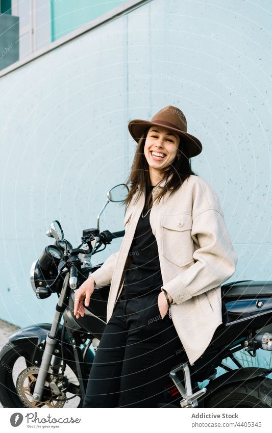 Motorradfahrerin in der Nähe eines auf der Straße geparkten Motorrads Frau Biker Reiter Bestimmen Sie cool selbstbewusst selbstsicher Fahrbahn Straßenrand