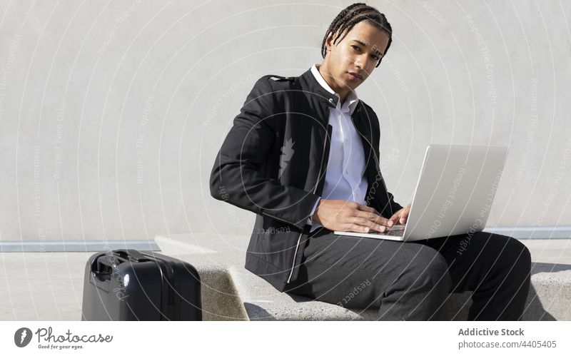 Mann mit Zöpfen benutzt Laptop auf der Straße Geflecht benutzend freiberuflich urban Stil Tippen abgelegen schwarz digital Afroamerikaner Geschäftsmann Arbeit