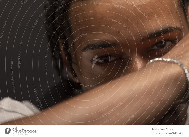 Ethnischer Mann mit Dreadlocks schaut in die Kamera Geflecht nachdenklich Starrer Blick Menschliches Gesicht Auge besinnlich Hipster Armband Porträt ernst