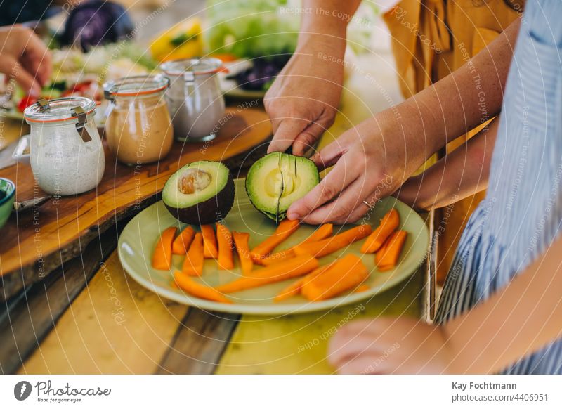 Bild von Händen, die eine Avocado schneiden Hintergrund Schönheit Holzplatte Schalen & Schüsseln Pflege Karotten Nahaufnahme Konzept Koch Essen zubereiten