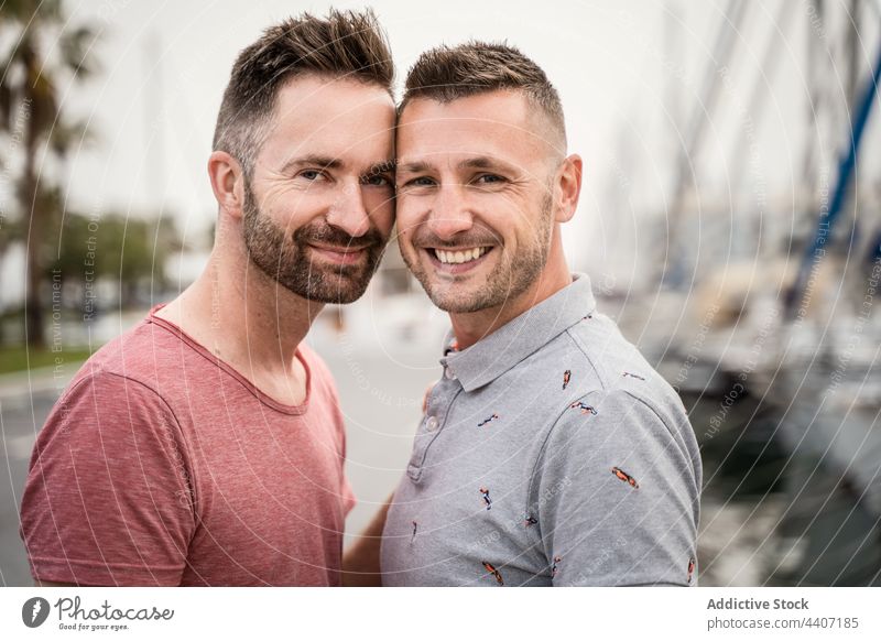 Fröhliche Schwule, die sich umarmen und in die Kamera schauen, auf einer städtischen Straße Paar gleichgeschlechtlich Umarmen Liebe sprechen Partnerschaft