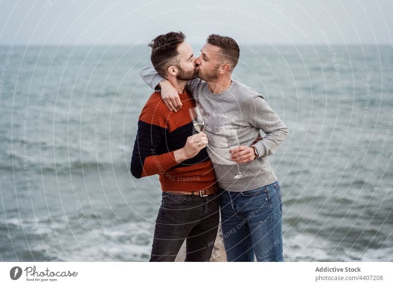Ein schwules Paar küsst sich am Meeresufer Kuss Champagne Getränk Alkohol genießen Partnerschaft Romantik Glas Männer lgbt Zeit verbringen romantisch trinken