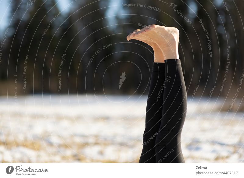 Nahaufnahme der Beine nackten Fußes der jungen attraktiven Frau übt Yoga auf verschneiten Feld Sport sportlich Sitzen meditierend Pose positionieren Schnee