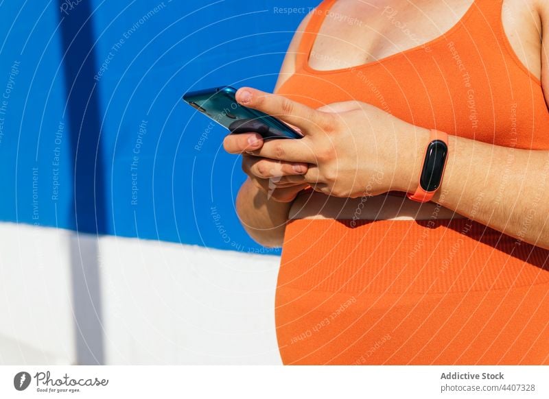 Anonyme übergewichtige ethnische Sportlerin mit Smartphone auf der Straße Pause freie Zeit Übergewicht herzlich Wand benutzend Apparatur Frau Gerät