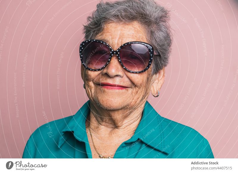 Stilvolle ältere Frau mit Sonnenbrille im Studio gealtert trendy modern Senior Lächeln Mode heiter Glück Zeitgenosse positiv Outfit froh graues Haar Kurze Haare