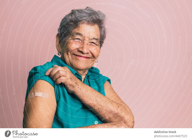Ältere Frau mit Gips am Arm nach Impfung gegen Coronavirus gealtert Impfstoff verputzen Fleck Lächeln heiter Senior Gesundheitswesen zeigen manifestieren