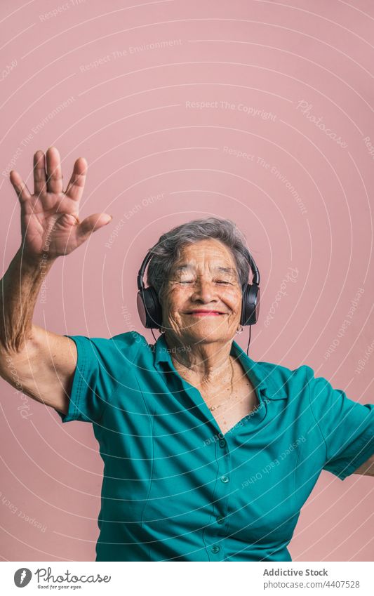 Glückliche ältere Frau, die mit Kopfhörern Musik hört Senior zuhören modern gealtert heiter Spaß haben Tanzen Stil Audio Klang genießen Gerät trendy positiv