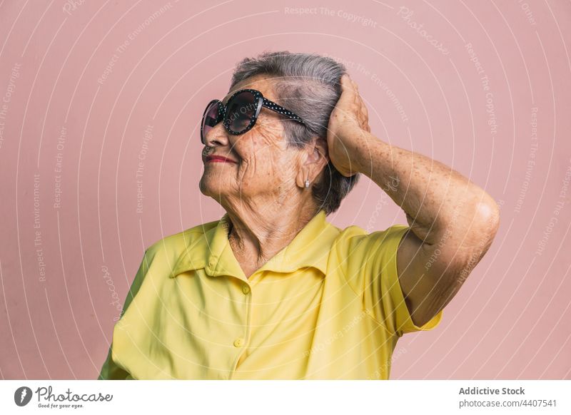 Stilvolle ältere Frau mit Sonnenbrille im Studio gealtert trendy modern Senior Lächeln Mode heiter Glück Zeitgenosse positiv Outfit froh Tastkopf graues Haar