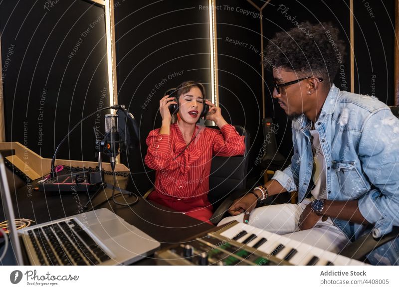 Gemischtrassige Kollegen nehmen im Studio Musik auf Musiker Aufzeichnen Atelier Zusammensein Mikrofon Gesang singen Sänger rassenübergreifend multiethnisch