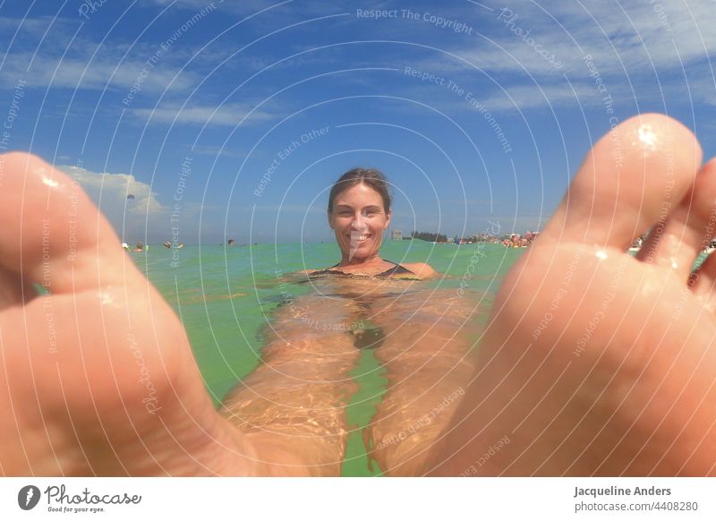 eine Frau liegt in Florida im Meer und hat die Füße vorne. Wasser Lügen Fuß Freude winken Schwimmen & Baden USA Ferien & Urlaub & Reisen Sonnenstrahlen Brandung