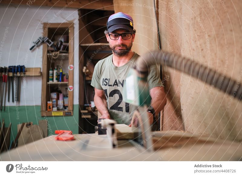 Fokussierter Tischler schneidet Holz an einer Sägemaschine im Arbeitsraum Zimmerer geschnitten Schiffsplanken Maschine präzise Werkstatt Mann Kunsthandwerker