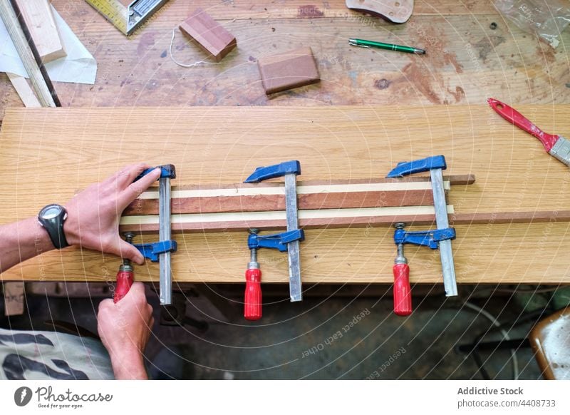 Handwerker beim Einspannen von Holzstäben in der Werkstatt Zimmerer einklemmen kleben Holzarbeiten Leim versammeln professionell präzise Instrument Mann