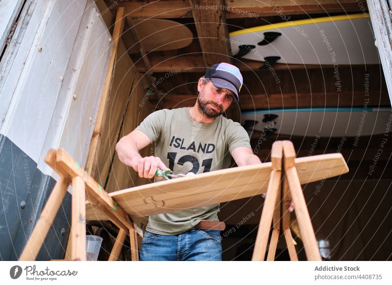 Holzarbeiter beim Auftragen von Klebstoff auf ein Brett für ein Longboard Tischlerin bewerben Handwalze Schiffsplanken handgefertigt Beruf Arbeit Mann