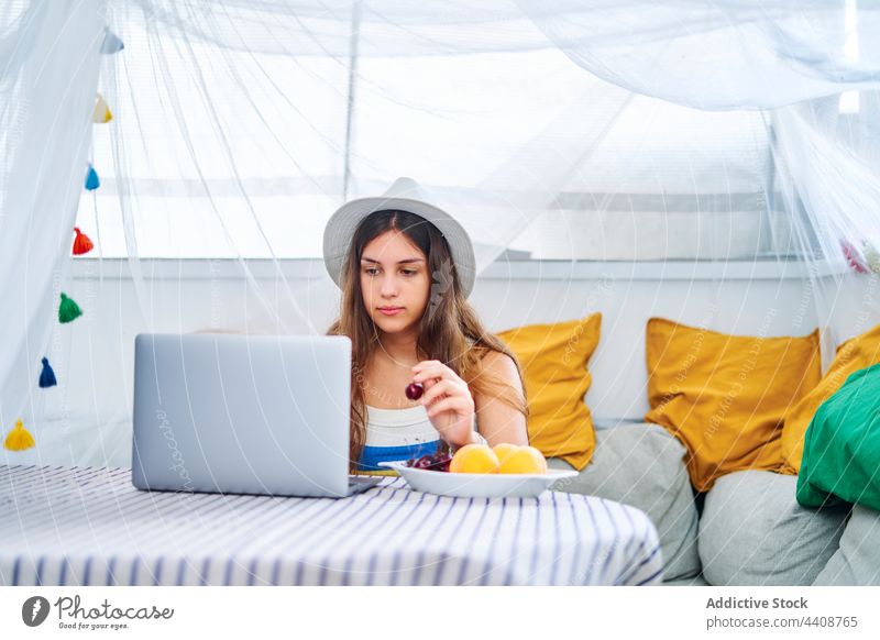 Frau isst Beeren und surft auf dem Laptop Browsen essen Kirsche Surfen benutzend Hinterhof Zelt Netbook Sommer Internet frisch genießen Wochenende Gerät