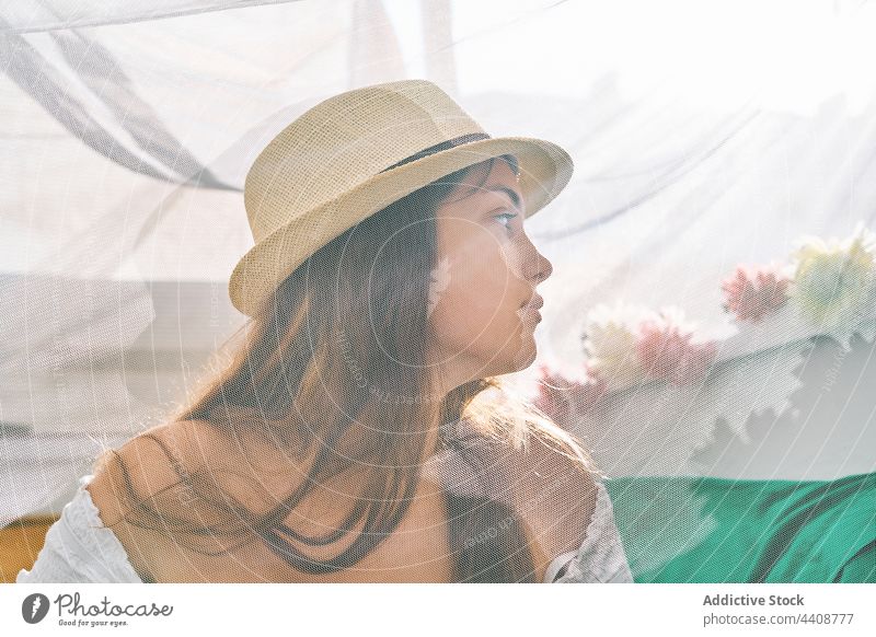 Junge Frau mit Sonnenhut sitzt im Zelt Sommer Inhalt Gardine jung Kälte genießen Hinterhof Lächeln ruhig friedlich durchsichtig Gelassenheit Harmonie