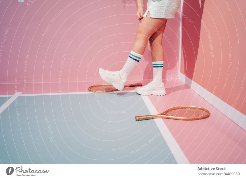 Crop-Spieler in Turnschuhen mit Tennisschläger auf dem Tennisplatz Remmidemmi Sport Stil Kniestrumpf Spaziergang Gericht Frau Sportlerin Ball kreativ Design