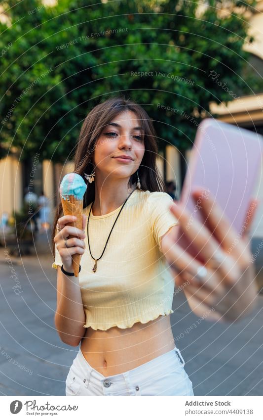 Lächelnde Frau mit Eiscreme, die ein Selfie mit ihrem Smartphone macht Speiseeis Dessert Leckerbissen Moment freie Zeit Straße benutzend Apparatur Gerät