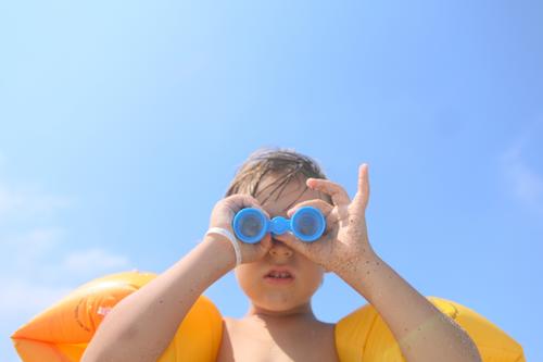 Kind schaut durch ein Spielzeugfernglas im Freien Wegsehen beobachten positiv Ufer Freiheit Urlaub Fernglas Seeküste genießend sorgenfrei Kindheit lässig